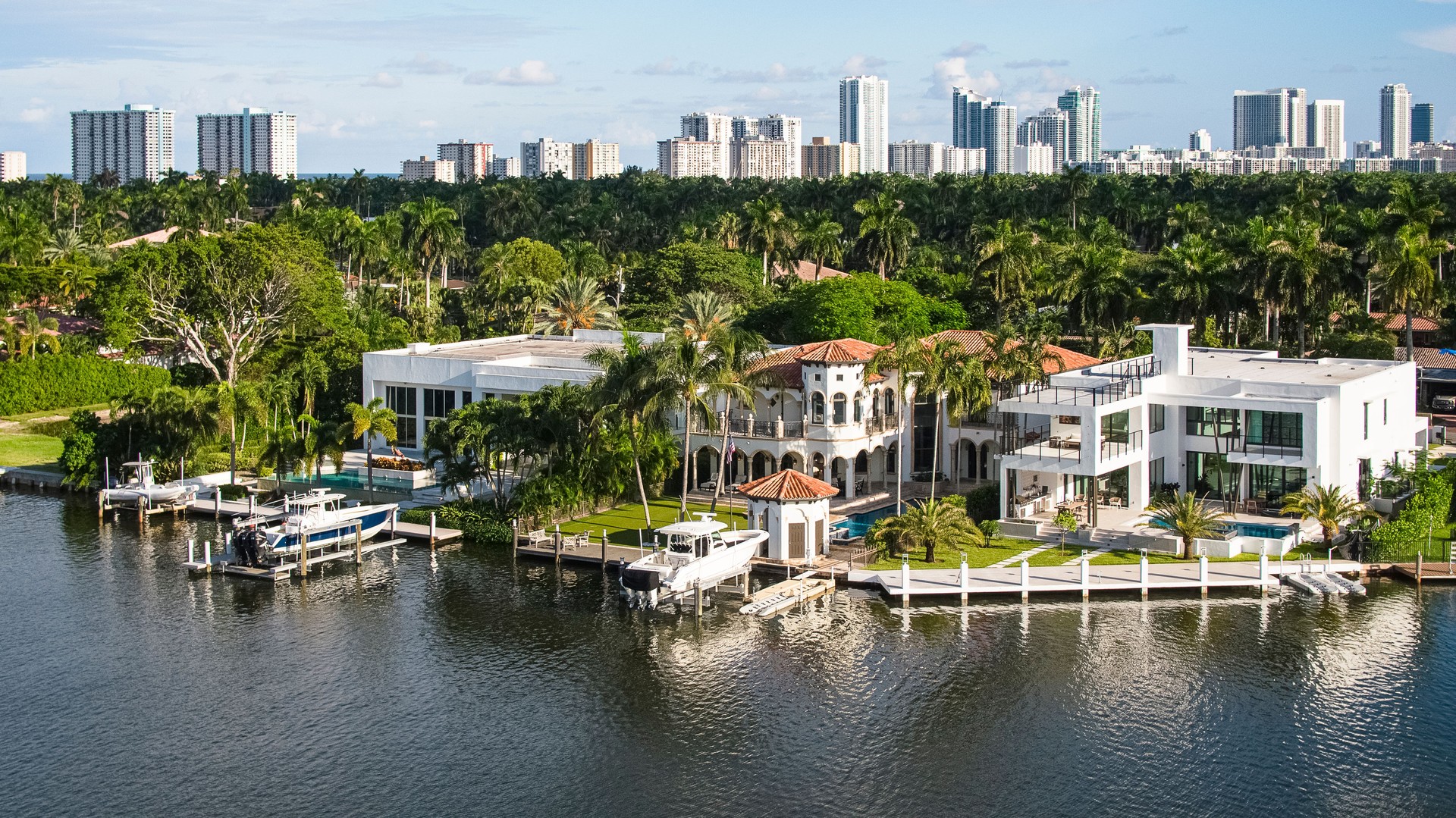 Wealthy coastal neighborhood with villas and mansions along the marina in Hollywood, Florida. Aventura suburbs and Sunny Isles modern buildings aerial view